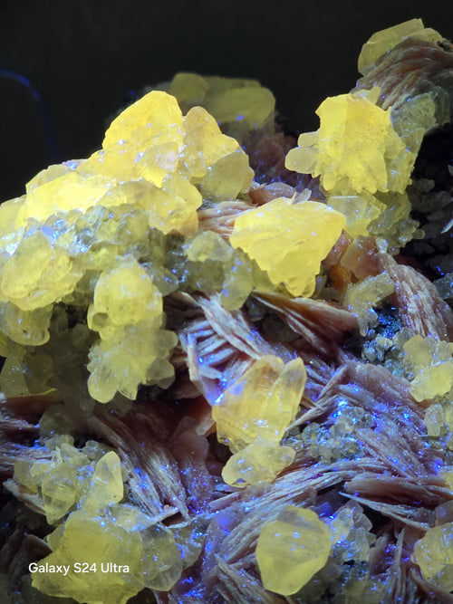 Bright yellow crystal clusters on reddish matrix, fluorescent under UV light