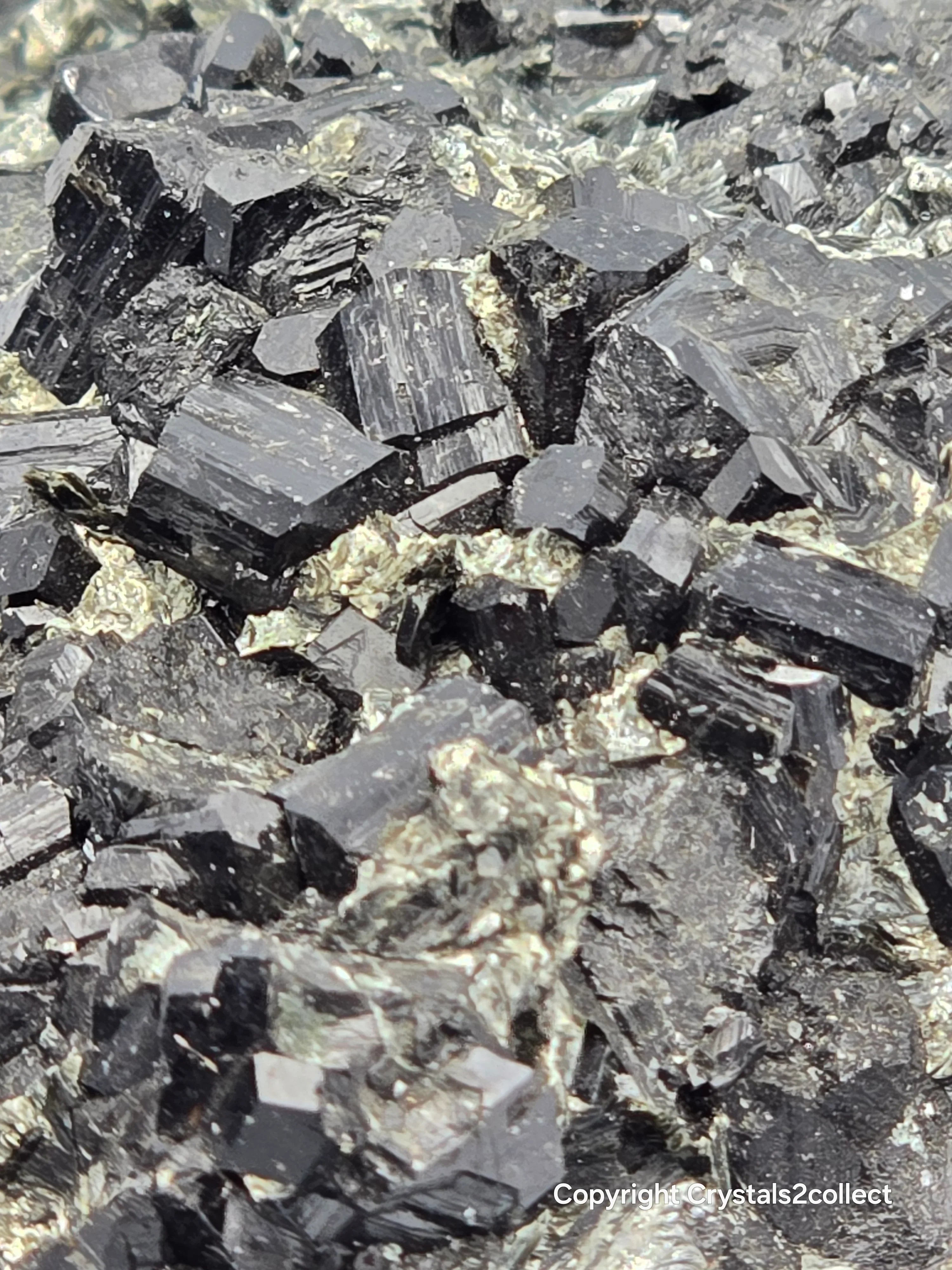 Hematite crystals with metallic luster, showcasing deep gray to black hues and distinct cleavage planes.