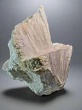 Stilbite crystal specimen with pink and green hues, showcasing natural mineral formation and striated texture
