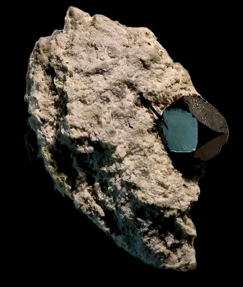 Fluorite crystal on matrix, showcasing vibrant blue-green color and geometric form against dark background