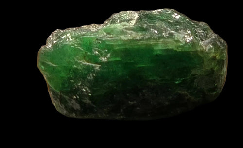 Emerald crystal specimen with rich green color and natural rough texture against black background