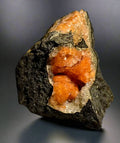 Orange calcite crystal cluster in dark matrix, natural mineral specimen for collectors