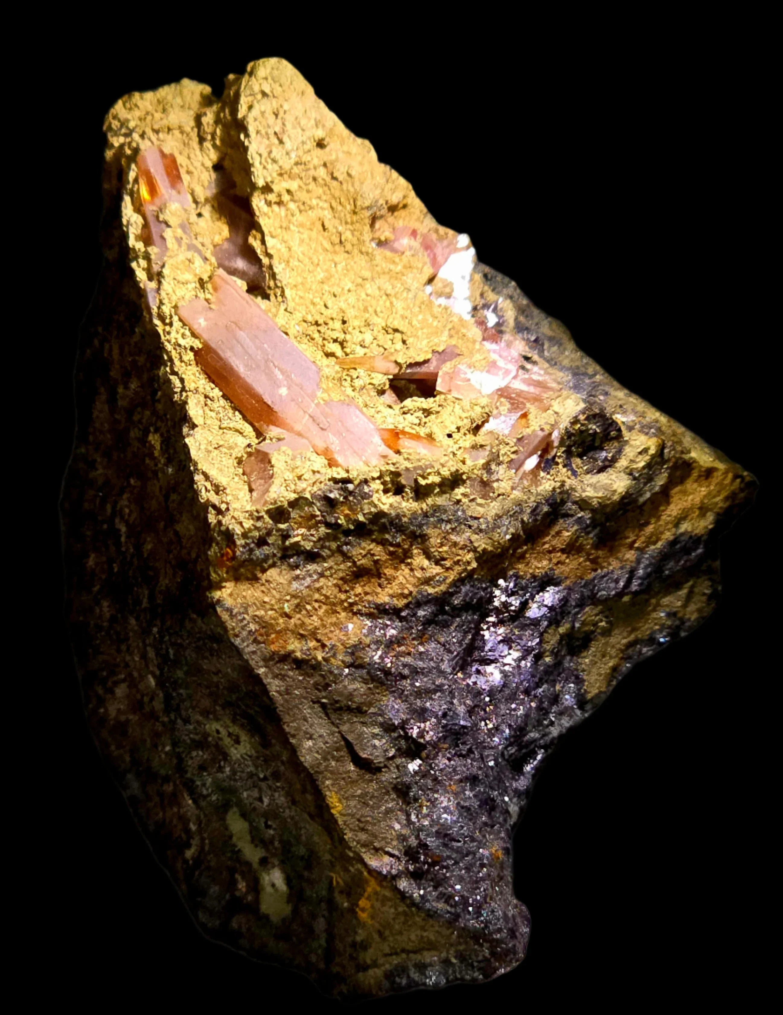 Aragonite crystals on matrix, showcasing translucent orange blades against earthy yellow and dark host rock.