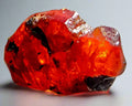 Vibrant red Spessartine Garnet crystal with black inclusions, showcasing natural mineral beauty