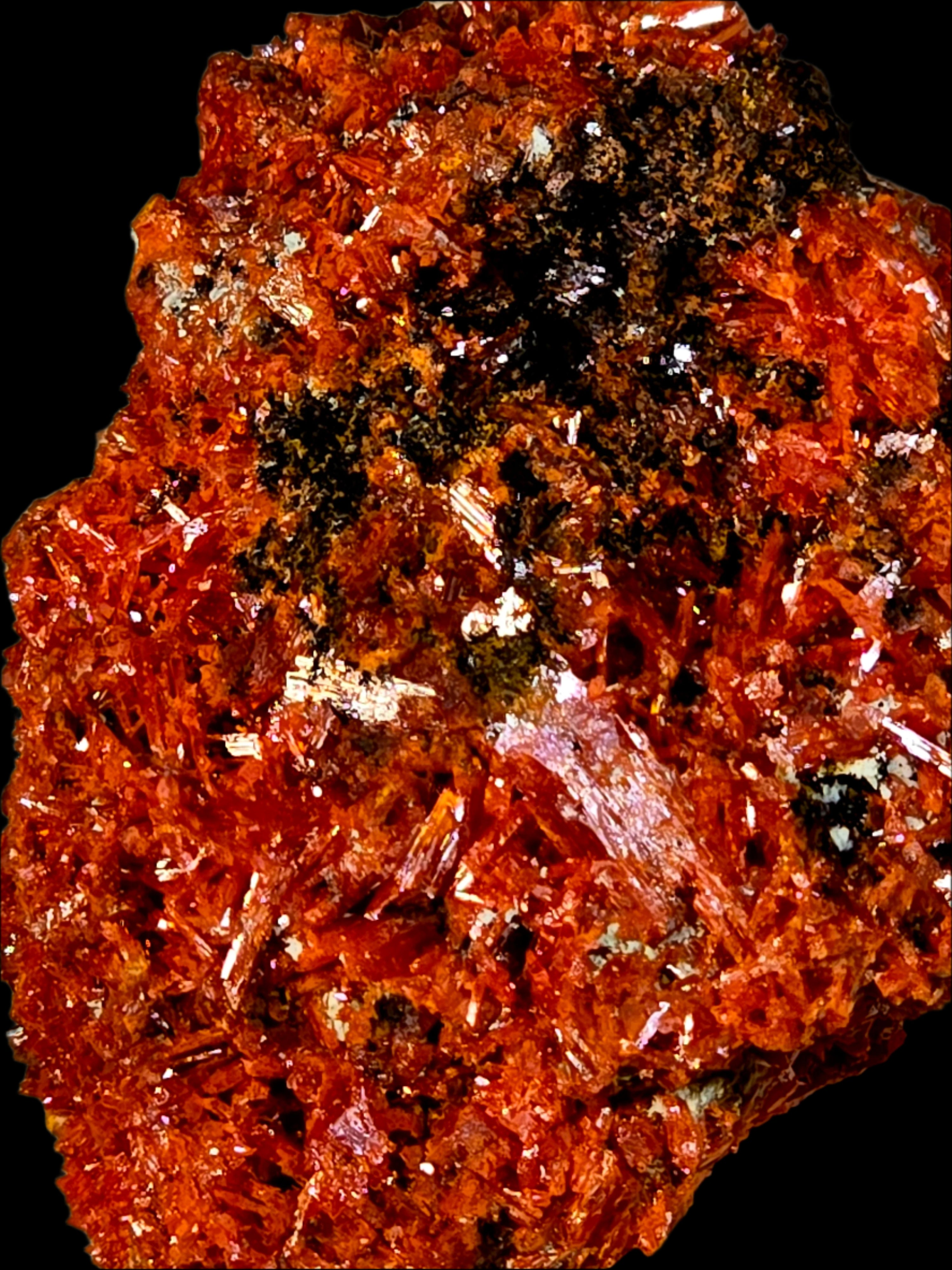 Close-up of a red-orange mineral specimen with black inclusions on a beige background