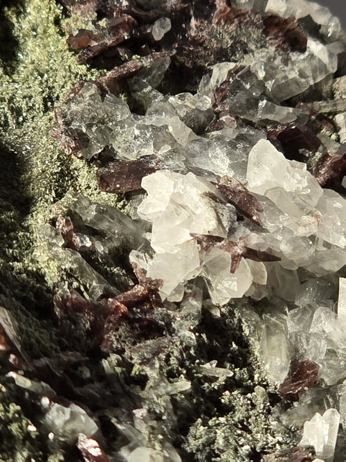 Clear quartz crystals with green and brown mineral inclusions, natural geological specimen