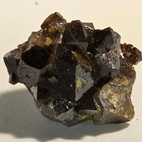 Andradite Garnet crystal cluster with metallic luster, showcasing deep brown to black hues and sharp geometric faces.