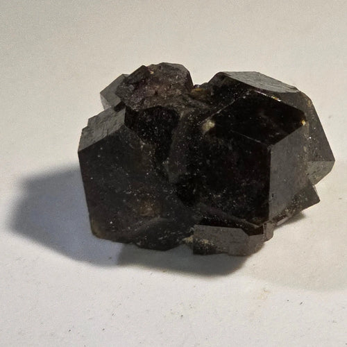 Fluorite crystal specimen with cubic formation, dark purple-black color, on white background