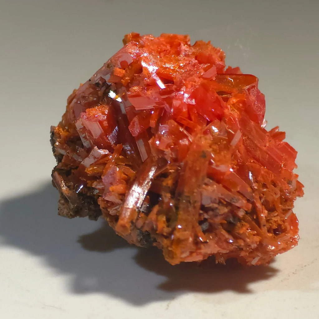 Vibrant red crystal specimen with sharp, glassy formations on dark matrix, ideal for mineral collectors
