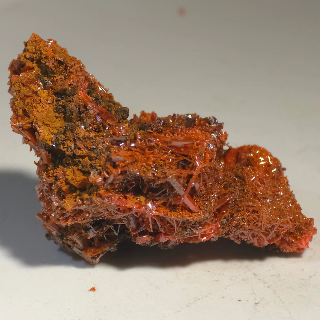 Crocoidite mineral specimen with vibrant orange-red crystals, fine needle-like formations, and earthy matrix