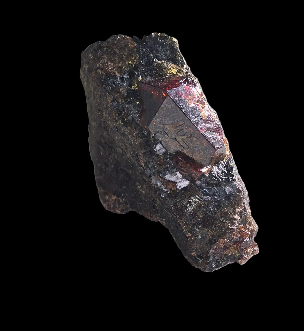 Garnet crystal on matrix, showcasing deep red facets and metallic luster against dark host rock