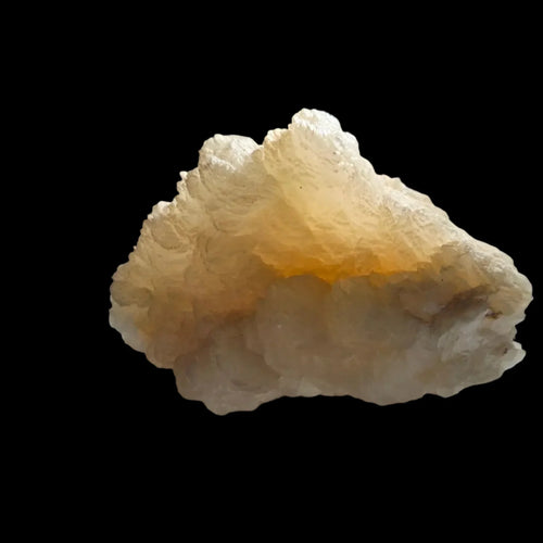 Calcite crystal specimen with creamy white and golden hues, rough natural formation against black background