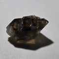 Smoky quartz crystal specimen with natural facets and inclusions, displayed on white background
