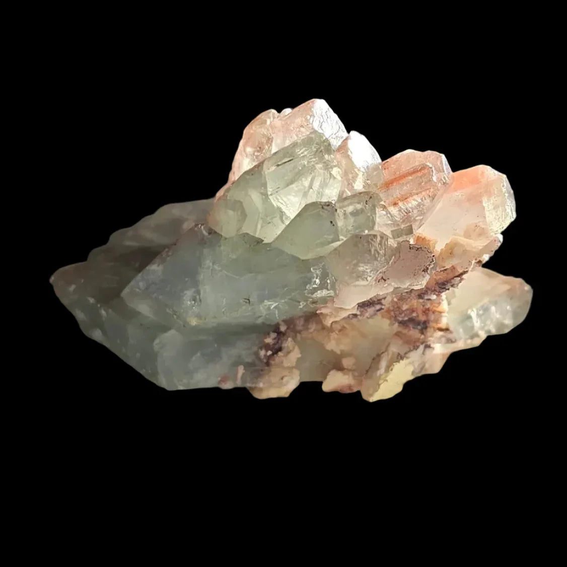 Fluorite crystal specimen with green and pink hues, natural mineral formation on dark background