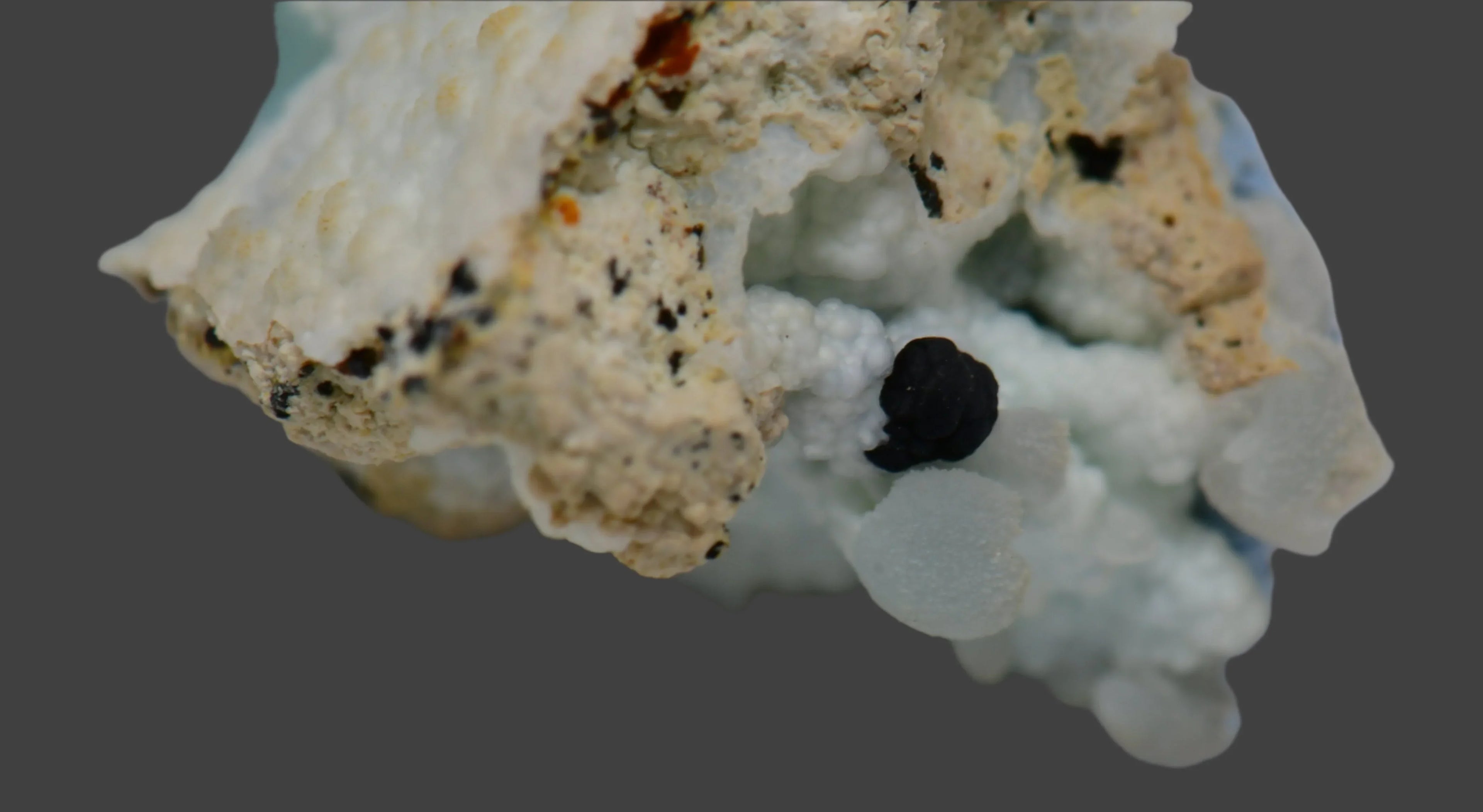 Hematite on quartz crystal specimen, showcasing dark metallic clusters against white mineral matrix