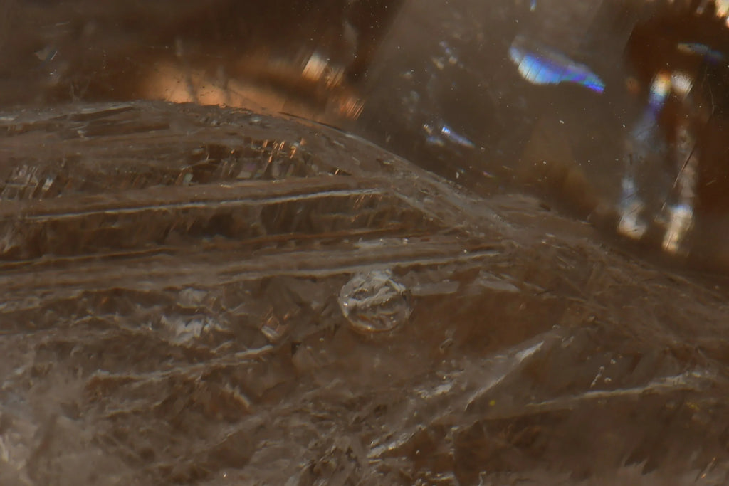 Smoky Quartz with visible striations and iridescent inclusions, showcasing natural crystal texture and geological detail.