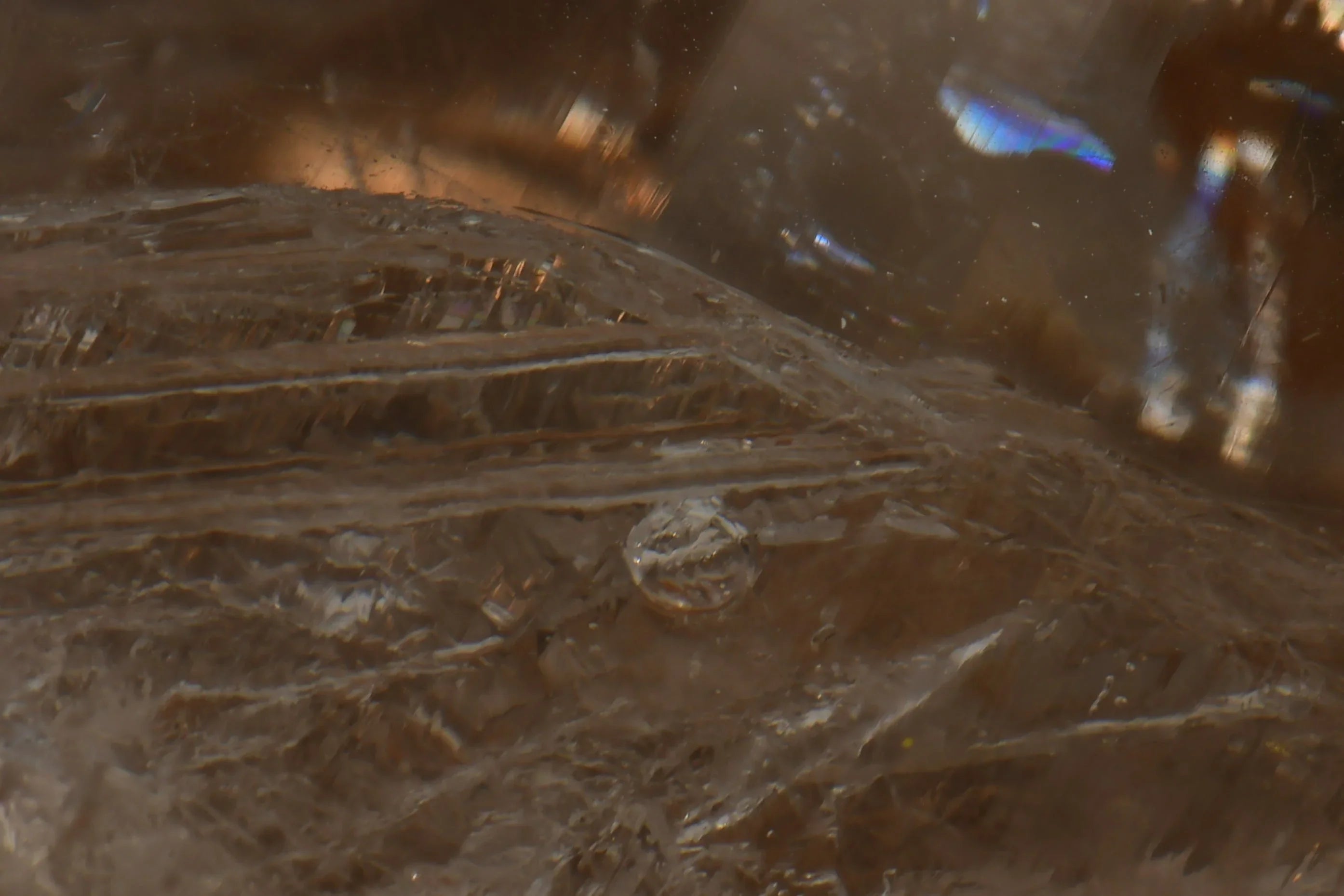 Smoky Quartz with visible striations and iridescent inclusions, showcasing natural crystal texture and geological detail.